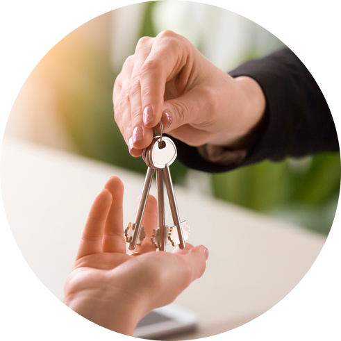A mão de uma pessoa entregando um molho de chaves de uma casa nova para a mão de outra pessoa